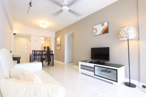 ein Wohnzimmer mit einem weißen Sofa und einem Flachbild-TV in der Unterkunft Cosy Stay Melaka in Malakka