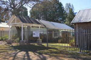 a fence in front of a building with a sign at Dullstroom Artist Cottages in Dullstroom