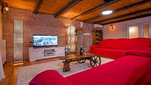 een woonkamer met een rode bank en een tv bij Villa Tomani in Krmed