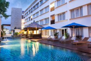 a hotel with a swimming pool with chairs and umbrellas at Natya Hotel Kuta in Kuta