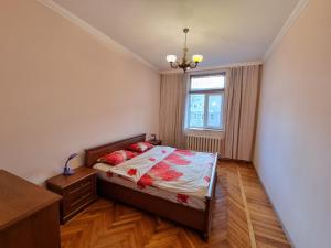 Schlafzimmer mit einem Bett mit roten Kissen und einem Fenster in der Unterkunft Grand Ultracentral Apartments Stefan cel Mare in the heart of Chisinau in Chişinău