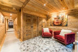 2 sillas rojas en un pasillo con paredes de madera en Le Lodge Rodzina, Luxueux chalet familial entièrement rénové avec Jacuzzi et Vue par LLA Selections en La Clusaz