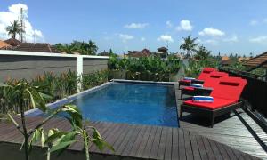 a patio with a pool and a red couch and chairs at Svarna Hotel in Sanur