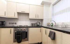a kitchen with white cabinets and a stove top oven at Bishopsgate House in Coventry