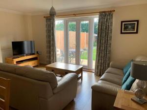 a living room with a couch and a tv at Cheerful 3 bedroom home close to beach and High St in Sheringham