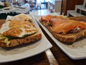 two sandwiches on white plates on a table at Hostal S'Algaret in Fornells