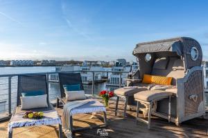 a deck with chairs and a grill on a boat at Schwimmendes Haus Schleikubus in Olpenitz