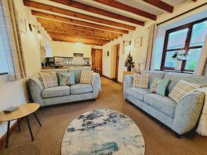 a living room with two couches and a table at Grosmont Cottage, Ruswarp in Whitby