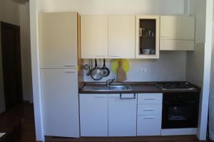 a kitchen with white cabinets and a sink and a refrigerator at Analogic tour - Appartamento Valleremita in Fabriano