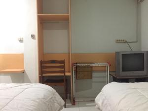 a bedroom with a bed and a desk and a tv at Losmen PUM Syariah at Desa Wisata Sabang in Sabong