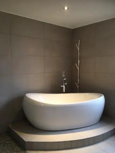 La salle de bains est pourvue d'une grande baignoire blanche. dans l'établissement La Maison du Petit Hutin, à Reims