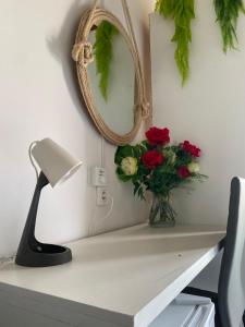 einen Schreibtisch mit einem Spiegel und einer Vase aus Blumen in der Unterkunft Christian Place in Praia