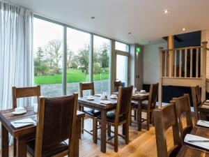 een eetkamer met tafels en stoelen en een groot raam bij Eagle Mill Luxury Rooms in Huntingdon
