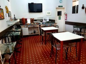 a restaurant with two tables and a counter with a tv at Hotel Casa Grande Itapira in Itapira
