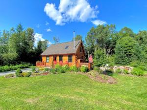 a wooden house on a field of grass at BC Log cabin with private beach river fire pit AC wifi onsite trails ski slope views in Carroll