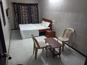 特里姆巴克Hotel Dhruv Palace的小房间设有一张床、两把椅子和一张桌子