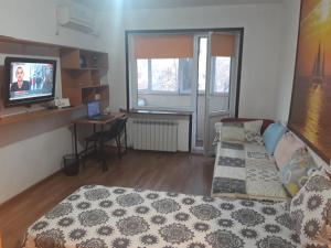 Schlafzimmer mit einem Bett, einem Schreibtisch und einem TV in der Unterkunft Apartments on Koktem 1 in Almaty