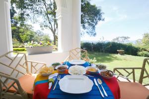 - une table avec des bols de nourriture sur une terrasse couverte dans l'établissement Dutch House Bandarawela, à Bandarawela