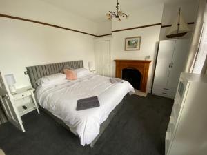 a bedroom with a large white bed with a fireplace at Cosy 2 Bedroom House -2022 & 2023 Award Winner! in Ramsgate