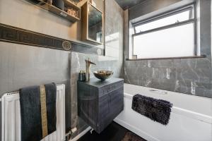 łazienka z wanną, umywalką i oknem w obiekcie The Medway Executive Apartment w mieście Gillingham