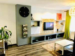 a living room with a tv and a clock on the wall at Zuzu’s home in Râşnov