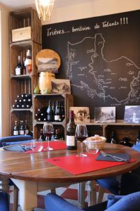 einem Holztisch mit Weingläsern und einer Tafel in der Unterkunft Auberge du Grand Champ in Lalley