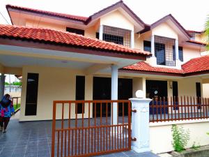 een huis met een hek en een vrouw die ervoor loopt bij D'View Guest Houses in Kuala Perlis