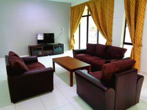 een woonkamer met 2 stoelen, een tafel en een tv bij D'View Guest Houses in Kuala Perlis
