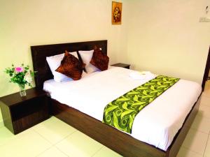 a bedroom with two beds with white sheets and a green blanket at D'View Guest Houses in Kuala Perlis