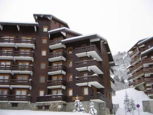 ein hohes Gebäude mit Schnee auf dem Boden davor in der Unterkunft Ski in and Out 2-Bed Apartment in Meribel in Les Allues
