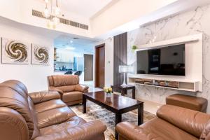 ein Wohnzimmer mit Ledermöbeln und einem TV in der Unterkunft Live spacious 3BR apartment all En Suite & Balcony in Dubai