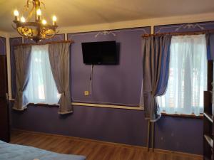 a bedroom with purple walls and curtains and a tv at Тороманова къща in Koprivshtitsa