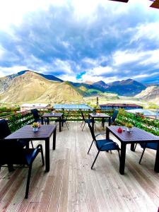 a deck with tables and chairs and a view of mountains at HOTEL KAZBEGI 1963 in Stepantsminda