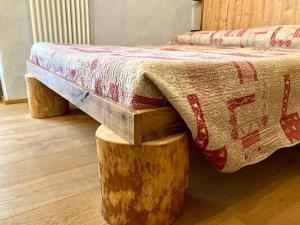 a bed with a comforter and two log stumpsoleranceangering at LA PLACETTE - Albergo diffuso e trattoria in Usseaux
