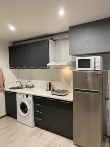eine Küche mit einem Kühlschrank, einer Waschmaschine und einem Trockner in der Unterkunft Pumpura apartment in Liepāja