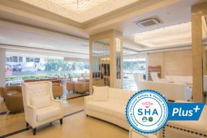 a lobby with white chairs and a sign that says shha plus at Avana Hotel and Convention Centre SHA Extra Plus in Bangkok