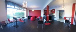 a living room with tables and chairs and a kitchen at Contact Hôtel du Cerf in Château-Gontier