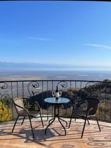una mesa y 2 sillas en un balcón con vistas al océano en Guest House Kusika, en Signagi