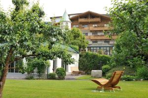 a building with a yard with two chairs in the grass at Hotel Herrschaftstaverne in Haus im Ennstal