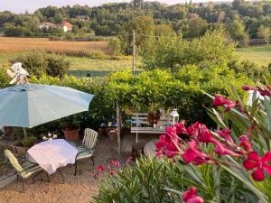 a patio with an umbrella and chairs and flowers at Oca Carolina in Buttigliera Alta