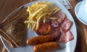 a plate of food with sausage potatoes and french fries at Baraka Home in Nairobi