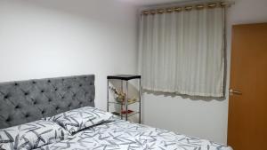 1 dormitorio con 1 cama con cabecero gris y ventana en Apartamento aconchegante à 200m Praia de Piçarras, en Piçarras