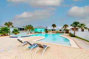 una piscina con sillas y palmeras en Reel Summer Place en Gulf Shores