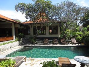 una piscina con sillas y una mesa junto a una casa en Besakih Beach Hotel, en Sanur