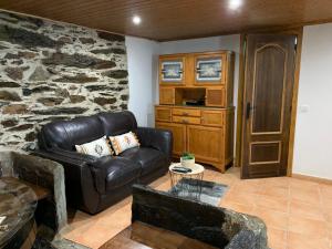 a living room with a leather couch and a stone wall at "Casa Do Avô Patrício" Mountain Experience in Parada