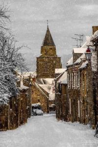 a snow covered city with a large building with a tower at LES BIGORNEAUX in Saint-Suliac