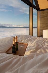 dos botellas y vasos en una bandeja en una cama en Iceland Lakeview Retreat en Selfoss