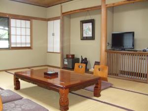 a living room with a coffee table and a tv at Marunaka Ryokan in Matsumoto