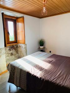 a bedroom with a large bed with a window at "Casa do Avô Armindo" Mountain Experience in Vila Real