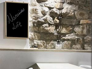 un mur en pierre avec un panneau devant un banc dans l'établissement Narnia Loft, à Narni